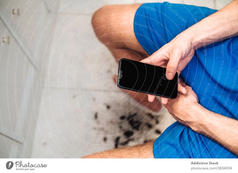 Young faceless man using smartphone while watching self haircut video in bathroom screen device use home concept alone independent hairdresser cellphone