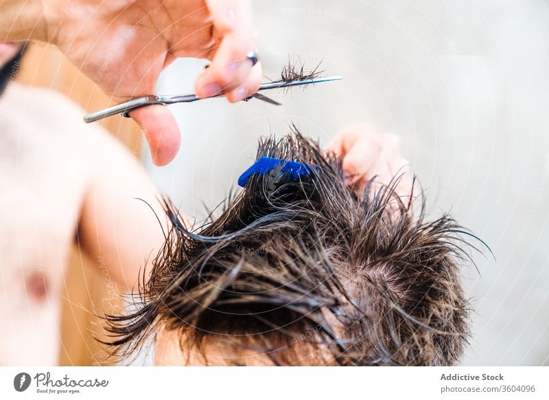 Crop barber clipping hair of man using hairdressing shears in bathroom cut tool home equipment hand scissors process hairdo haircut comb hairdresser male