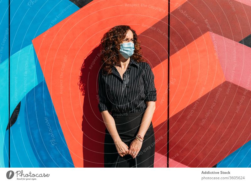 Woman with face mask in front of a wall with bright colors. epidemic people coronavirus woman protection flu covid-19 sick disease health street infection