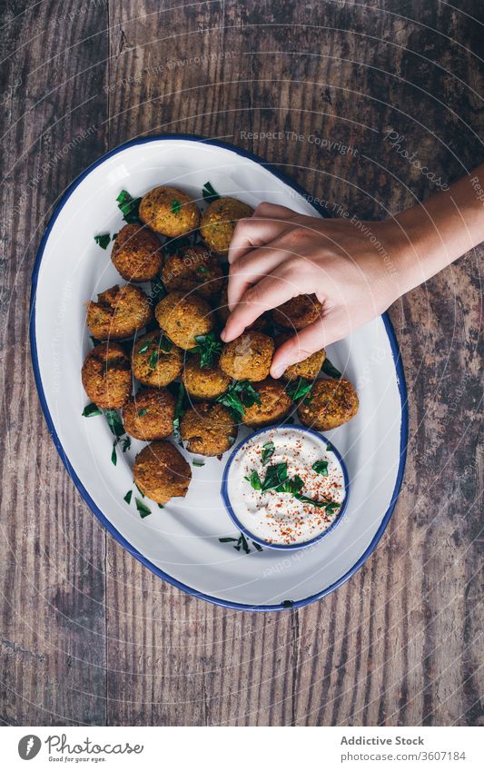 Crop person taking falafel ball from plate dish middle east cuisine treat try restaurant delicious portion calorie sauce savory cream gourmet vegetarian