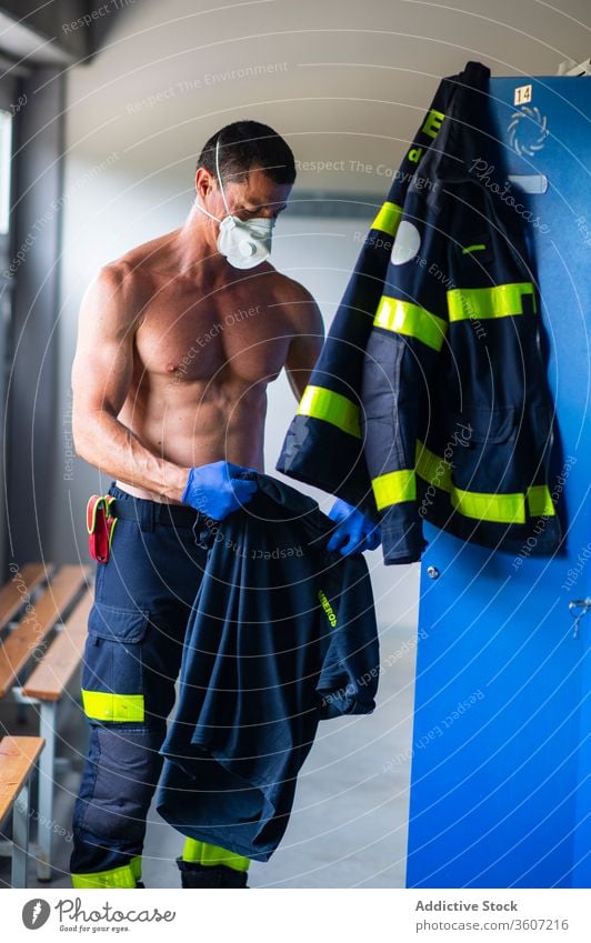 Senior male firefighter at fire station fireman work respirator safety senior strong locker naked torso serious prepare stand muscular face mask professional