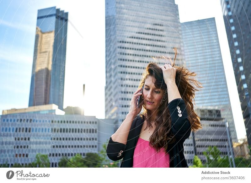Adult woman talking on smartphone in city businesswoman content elegant speak skyscraper using female center jacket work cellphone conversation call device