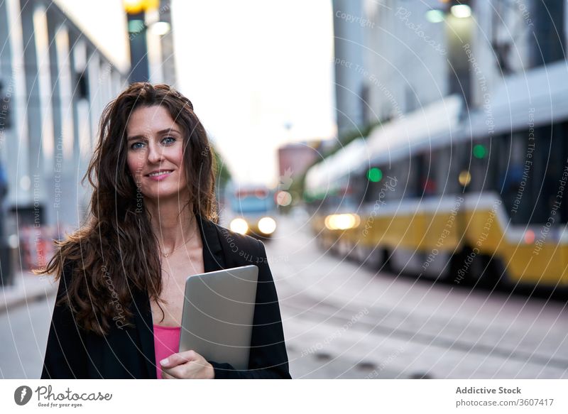 Businesswoman with laptop on city street entrepreneur businesswoman confident cityscape formal well dressed professional female cheerful content smile determine