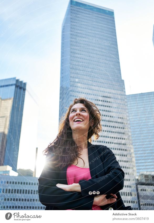 Determined smiling businesswoman against skyscrapers in downtown determine professional confident city thoughtful entrepreneur high rise elegant female urban