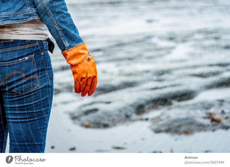 Volunteers wear jeans and long sleeved shirts and wear orange rubber gloves to collect garbage on the beach. Beach environment. Woman cleaning the beach. Tidying up rubbish on beach.