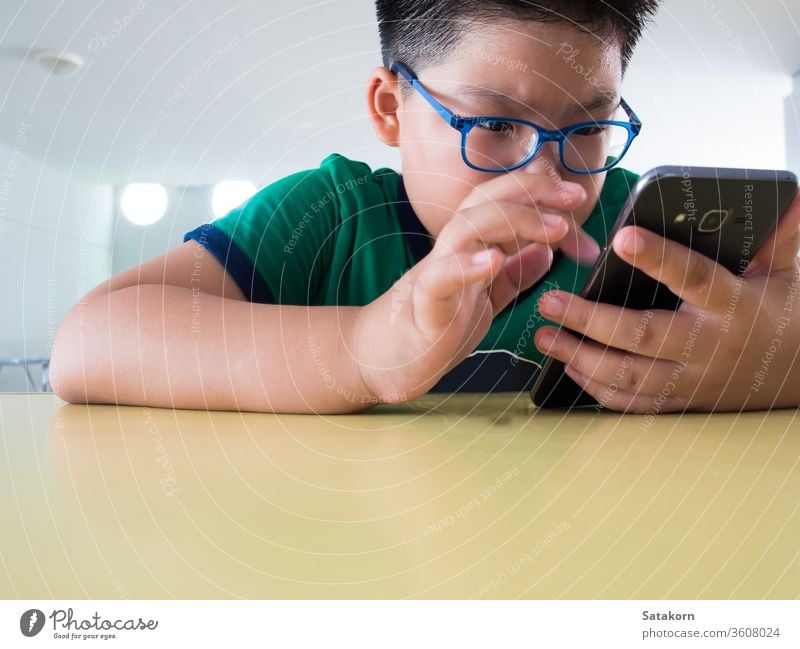 Serious boy playing on smartphone children serious game sweat asian kid hand technology telephone perspiration young earnestly internet mobile person little
