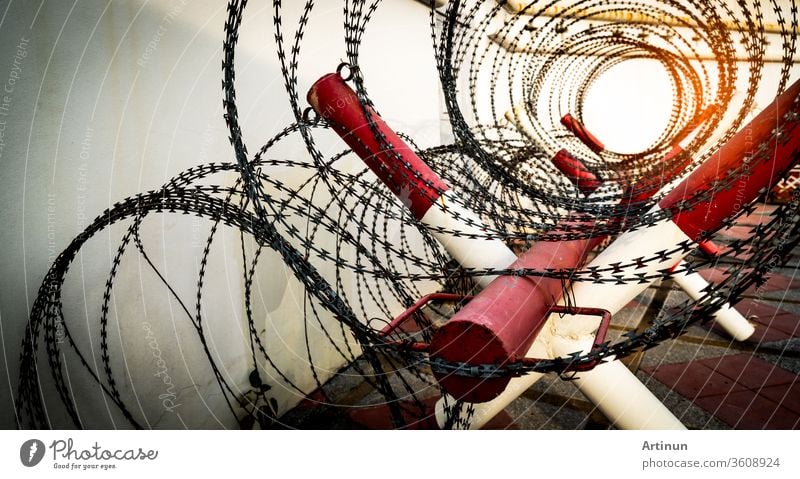 Barbed wire fence. Prison or jail wall. Security system. Private zone or danger military zone. Forbidden gate or entrance. Prohibited area. Red and white color on pole with rolled barbed wire fence.