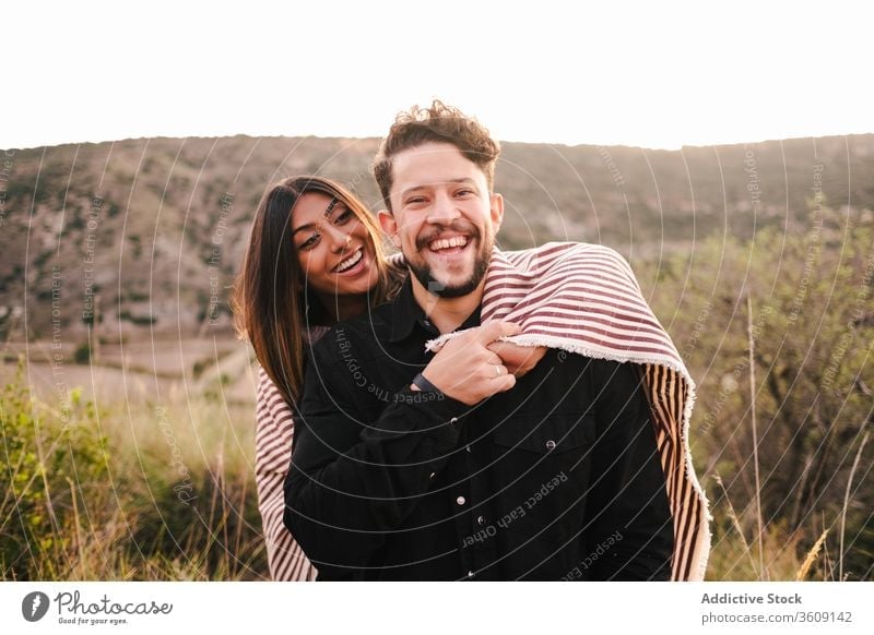 Delighted multi ethnic couple on hill laugh joke together having fun mountain hugging cheerful relationship multiethnic multiracial diverse love girlfriend