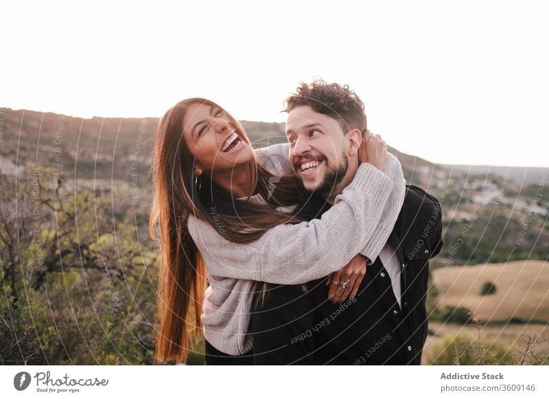 Delighted multi ethnic couple on hill laugh joke together hugging having fun mountain holding hands cheerful relationship multiethnic multiracial diverse love