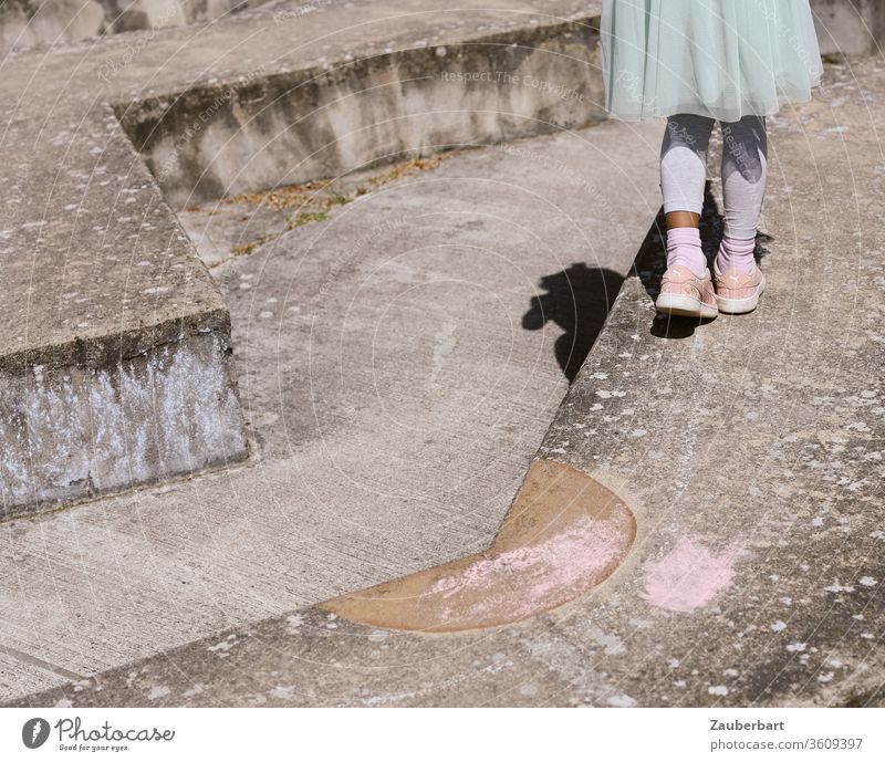 Legs of a girl in pink sneakers and tulle skirt on a concrete floor sculpture Pink Child Concrete Sculpture Stairs Stage jerk Tulle Labyrinth balance Playing