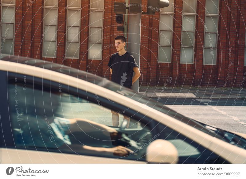 portrait of a lonely young man where a car drives through the picture adolescent beautiful boy building casual caucasian confident culture future issues