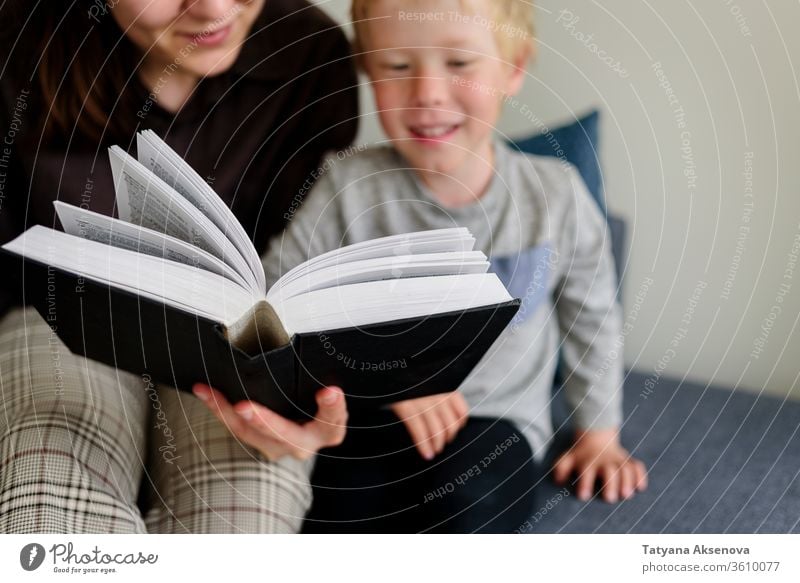 Mother and child reading book and smiling mother family home together happy childhood people parent woman female kid caucasian education happiness indoors mom