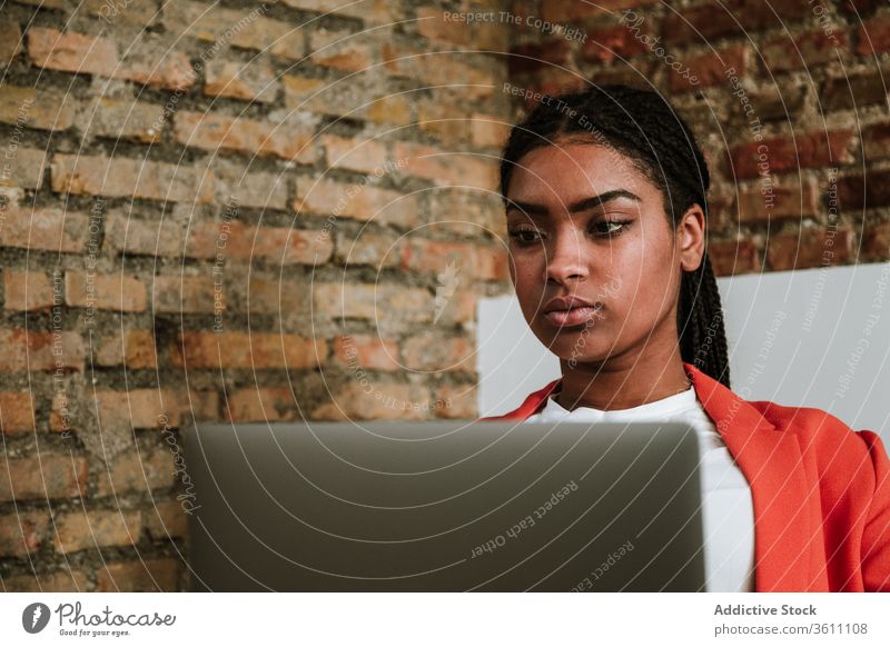 Modern black woman with computer in armchair business laptop online elegant loft design focus interior freelance modern device gadget internet using browsing
