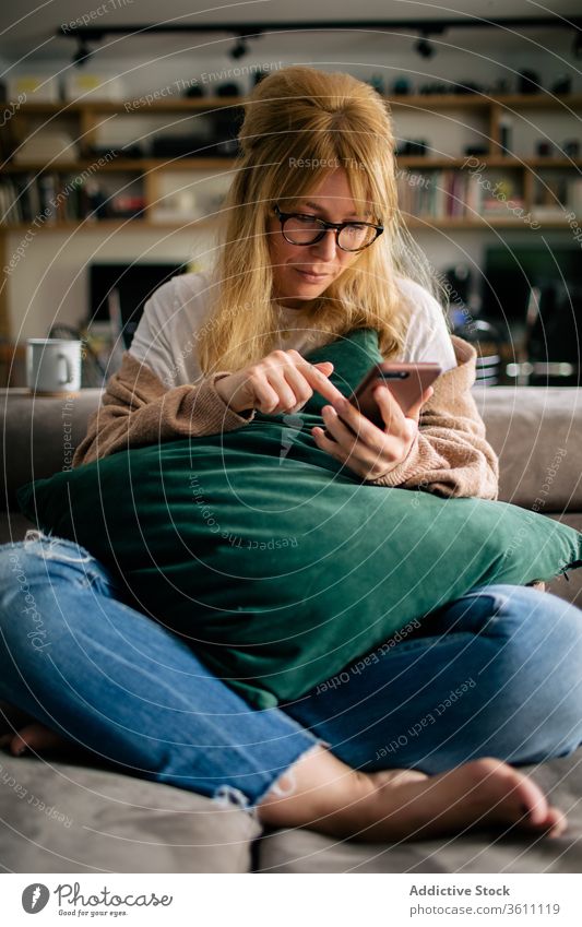 Crop woman browsing smartphone at home surfing cellphone weekend entertain using touch screen female cozy device cushion gadget internet online social media