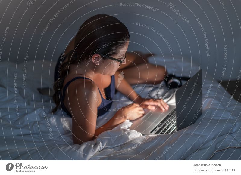 Woman in the computer on bed woman relax using female browsing blanket lying down tank top device technology laptop gadget rest internet home lady cozy comfort