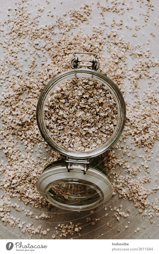Organic rolled oat and a glass of jar on grey background. Healthy breakfast ingredient for porridge. Full with vitamins, minerals and fibre. food texture