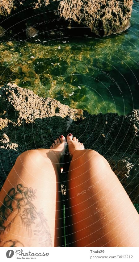 girl with tattoo sitting on the sea rocks after swimming, legs and sea travel closeup water beautiful summer beach ocean lifestyle people relaxation rest foot