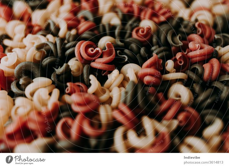Spiral dried pasta in three different color food healthy italian meal closeup red yellow macaroni sweet green salad fresh cuisine vegetable ingredient raw