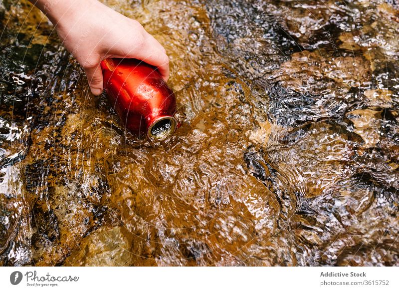 Anonymous woman taking water from brook in forest bottle clean style green female outerwear creek nature relax lifestyle countryside informal thirsty