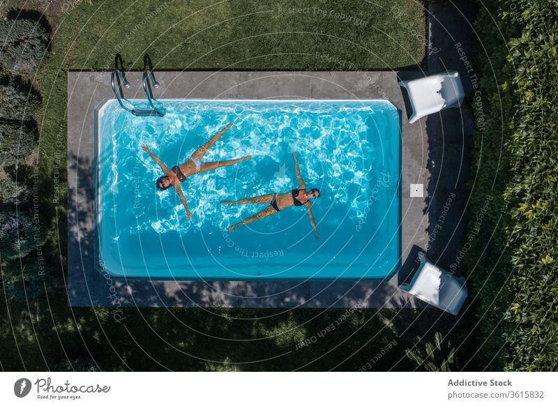 Relaxed women floating in pool relax lying summer rest chill water yard backyard female lifestyle holiday friend together recreation poolside sunbath carefree