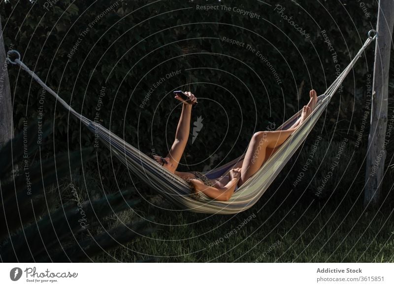Happy woman taking selfie in hammock smartphone happy lying summer carefree chill enjoy young female cheerful relax rest vacation holiday lifestyle smile using