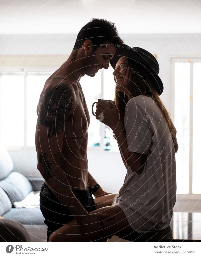 Couple in love hugging in modern apartment couple morning sensual together table coffee relationship shirtless tender girlfriend boyfriend cup beverage romantic