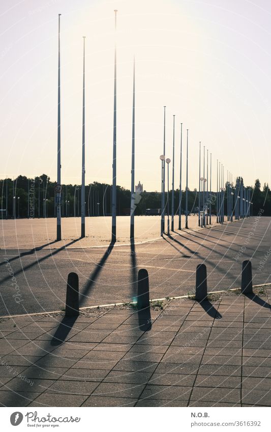 Empty square with flagpoles against the light Back-light Sun Shadow Flagpole Retro Deserted Light Sunlight Day Beautiful weather Sky Exterior shot Colour photo