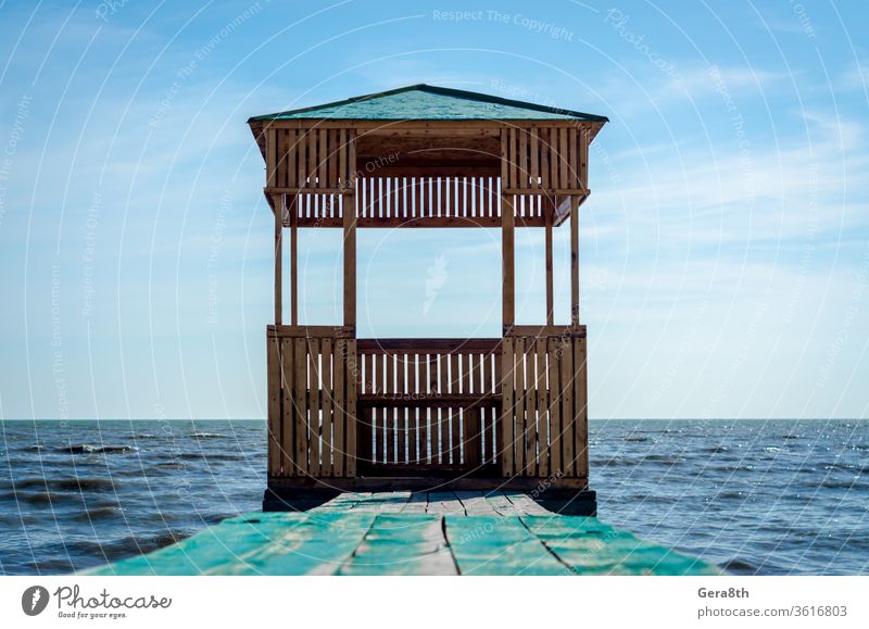 wooden arbor on the background of the sea and blue sky with clouds boards building gazebo nature old painted roof seascape surface water waves wooden gazebo