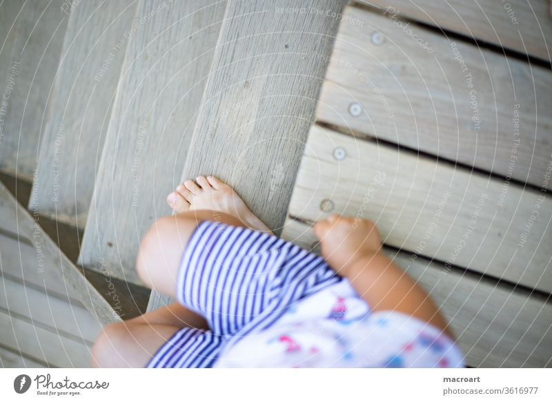 Playground - child cut sideways sitting on wooden stairs Child s sedentary wooden staircase Stairs Wood Summer short pants klienkind recognize Boredom