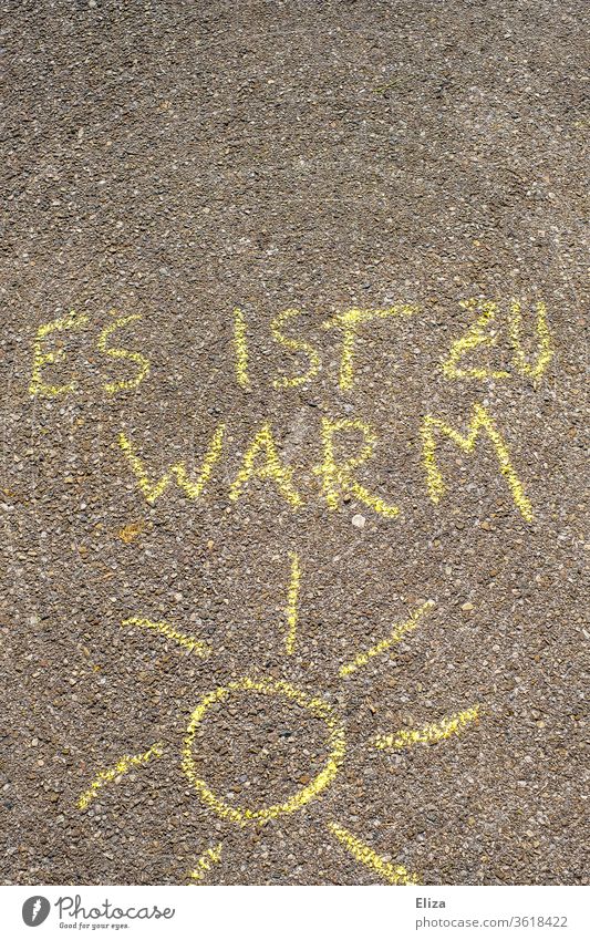 Sun painted with street crayon and the text "it is too warm". Concept global warming, sweating and heat. Global warming ardor perspire sunshine Chalk drawing