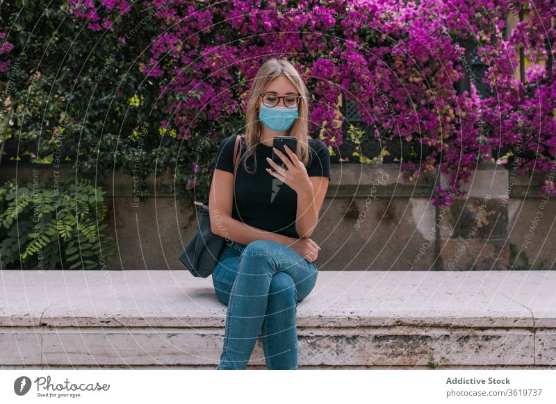 Young woman using the smartphone and wearing a face mask outdoors pandemic street corona virus protection young city person crisis worried distance sitting girl