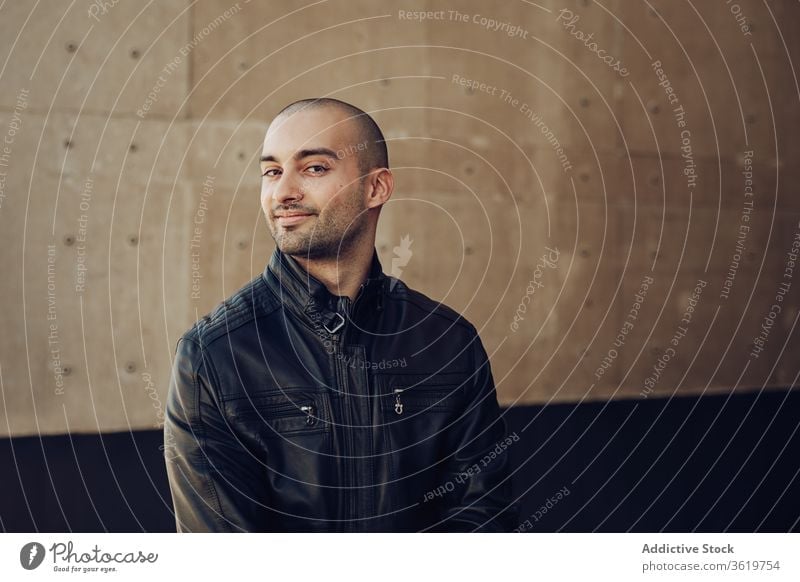 Stylish young man standing near building confident style casual modern bald wall urban street male black jacket trendy guy contemporary handsome happy fashion