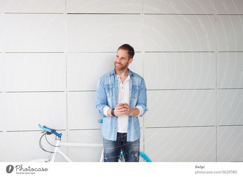 Casual guy next to a vintage bicycle with the mobile phone young man urban lifestyle person male city outdoors hipster bike cell technology street casual