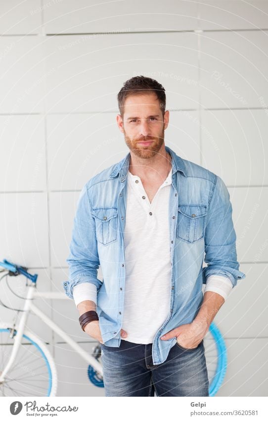 Casual guy next to his bike looking at camera bicycle hipster lifestyle urban young man background handsome male casual blue pensive think fashion person happy