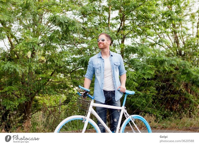 Handsome man enjoying with his bike in the park casual lifestyle male guy young leisure bicycle summer people active adult person urban caucasian outside sport