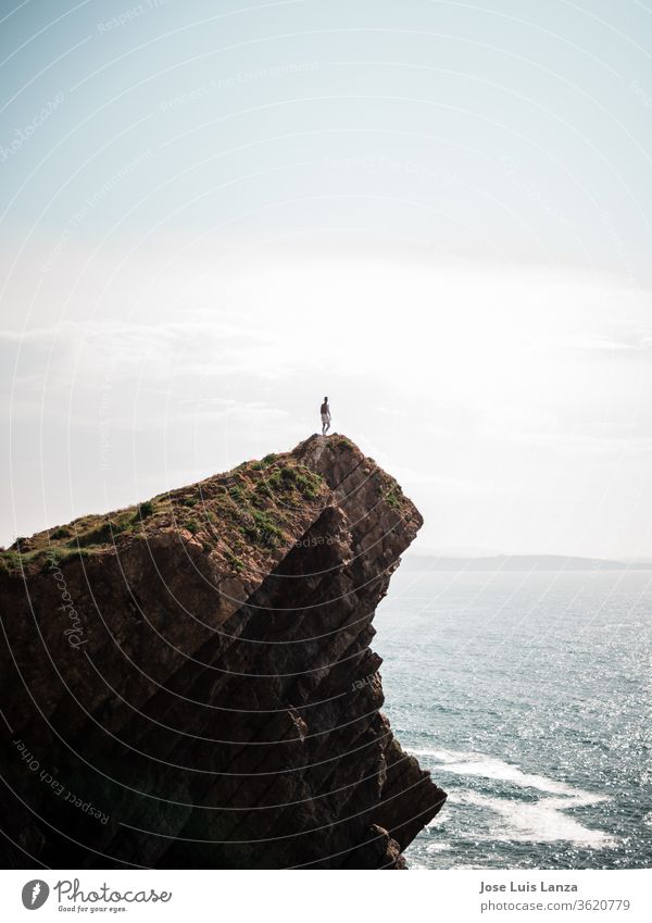 Silhouette of person on top of sea cliff silhouette ocean adventure extreme nature high rock success freedom sky man mountain sun sport male active outdoor
