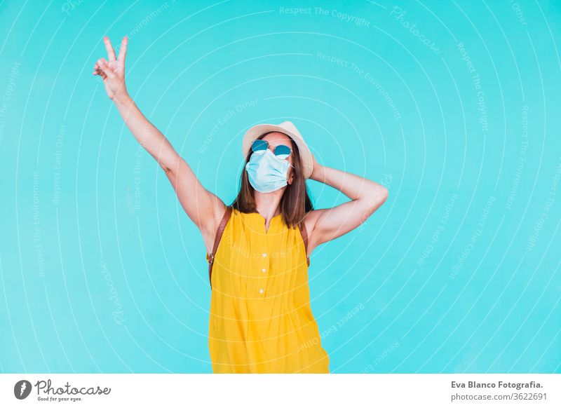 portrait of young woman outdoors over turquoise background wearing protective mask. Summer time and corona virus concept epidemic attitude saying infectious