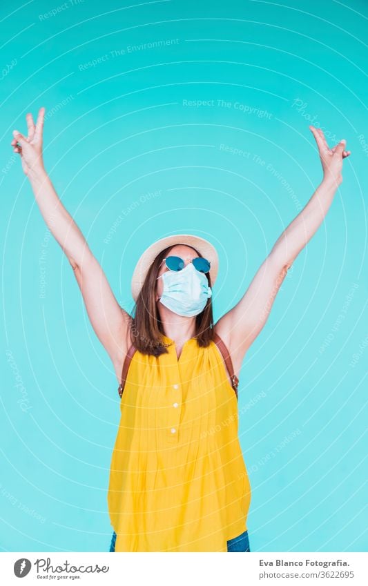 portrait of young woman outdoors over turquoise background wearing protective mask. Summer time and corona virus concept epidemic attitude saying infectious