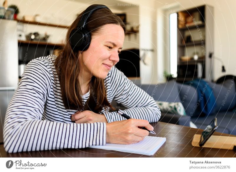 Woman in headphones learning at home education online e-learning distance watching listening student homework internet studying technology lesson portrait