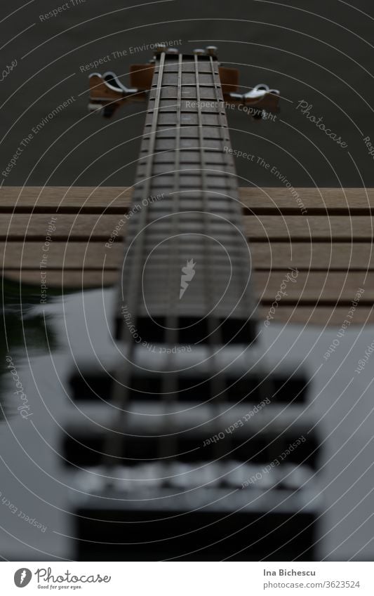 An electric bass neck photographed from side holder towards the head. The instrument is black, the focus is on the fingerboard and on the four sides. EBass