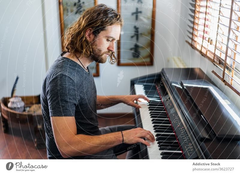 Talented man playing piano at home synthesizer musician instrument electronic talent male skill apartment cozy sit melody sound style entertain modern song guy