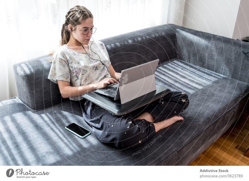 Young woman with headphones using laptop at home earphones young listen watch gadget online student casual video device internet browsing lifestyle connection