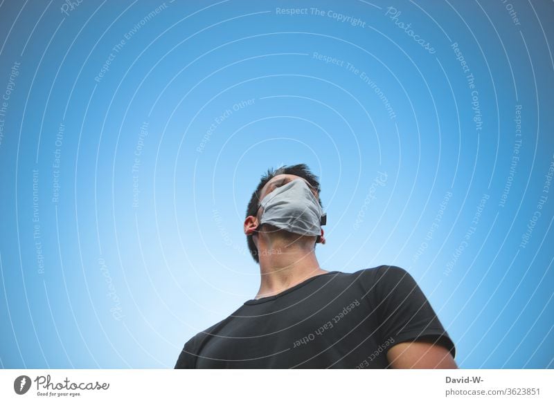 Man with a breathing mask looks thoughtfully at the sky Think thoughts anxiously Mask guard sb./sth. Respirator mask Risk of infection Panic Fear Human being