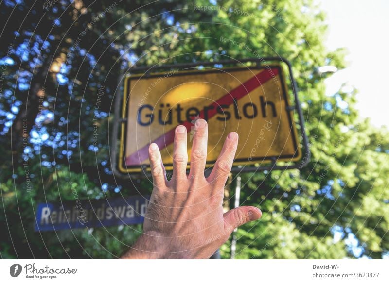 Man holds hand in front of the exit sign of Güterloh / halt Stop Gütersloh Rheda-Wiedenbrück Oelde cordon keep sb./sth. apart gap Safety covid-19 Tönnies