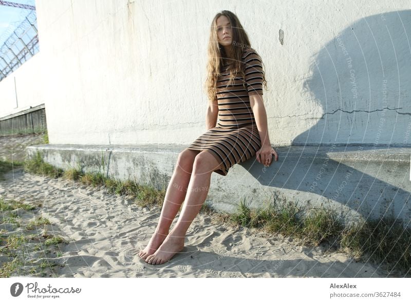 Portrait of a young woman at the beach on a concrete wall Intensive girl Adults portrait Day Skin Sunlight Self-confident Central perspective Young woman