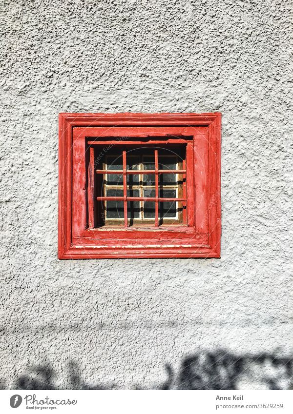 She was fascinated by the small red window on the grey wall. She stood in front of it for a long time and still discovered the small.n shadow opposite. Window