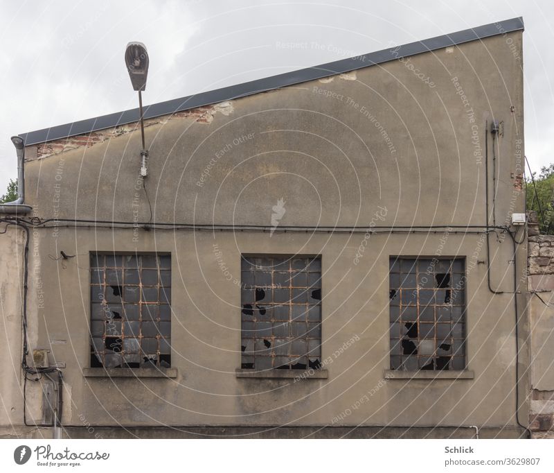 Old facade of a factory building with broken windows and exterior lighting Industry Facade Window Broken burst Exterior lighting low saturation of colors