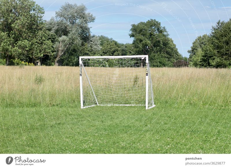A white football goal on a meadow next to a field. Leisure sports Soccer Goal recreational sport soccer Net White Meadow Sports Football pitch