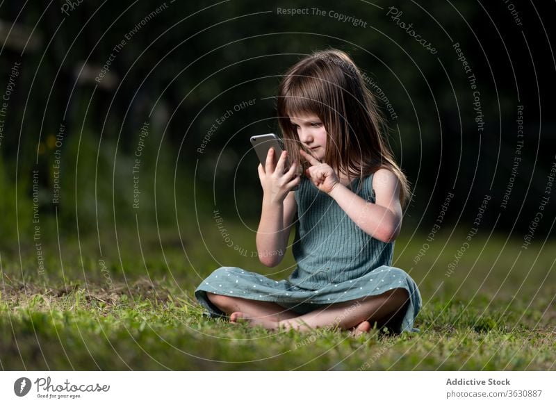 Girl browsing smartphone in park girl amazed shock surprise news read using lawn kid child summer green childhood chill meadow expressive disbelief female