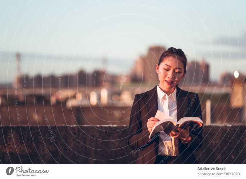 Young busy woman reading book on rooftop businesswoman modern young formal urban break rest asian female ethnic lifestyle smart contemporary intelligent